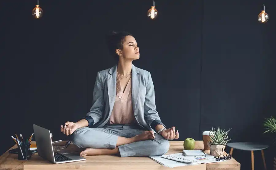 persona meditando en posición de loto junto a un lago